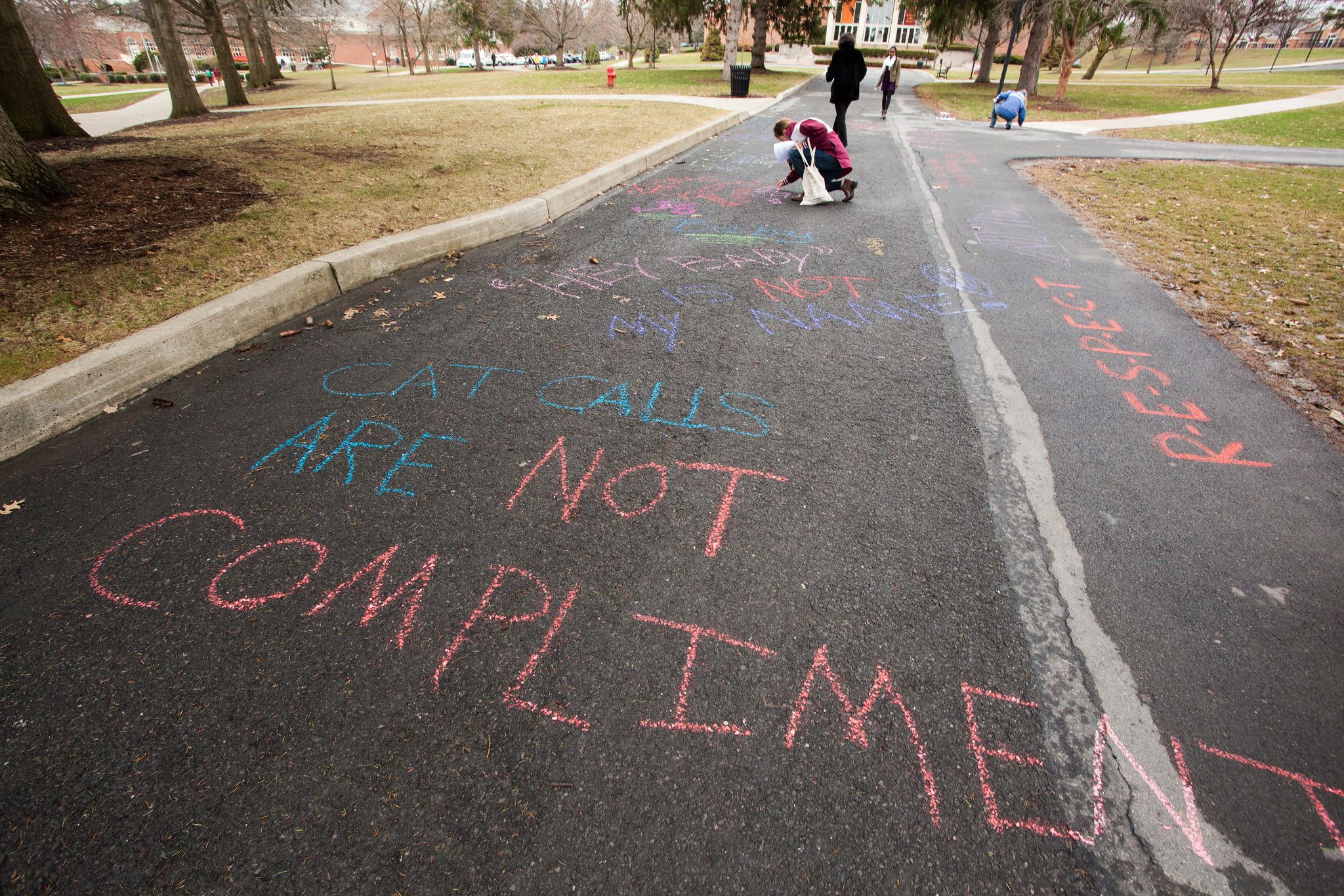 Street with chalk art that says, "Cat calls are not compliments."